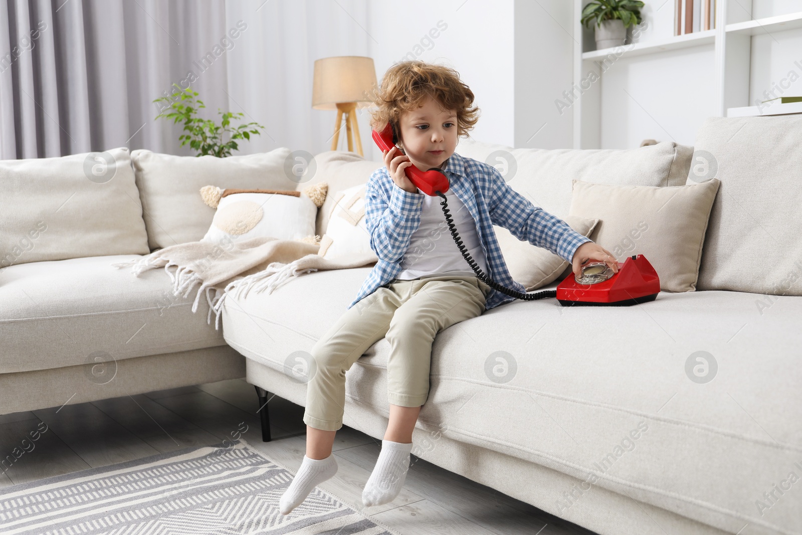 Photo of Cute little boy with telephone on sofa indoors