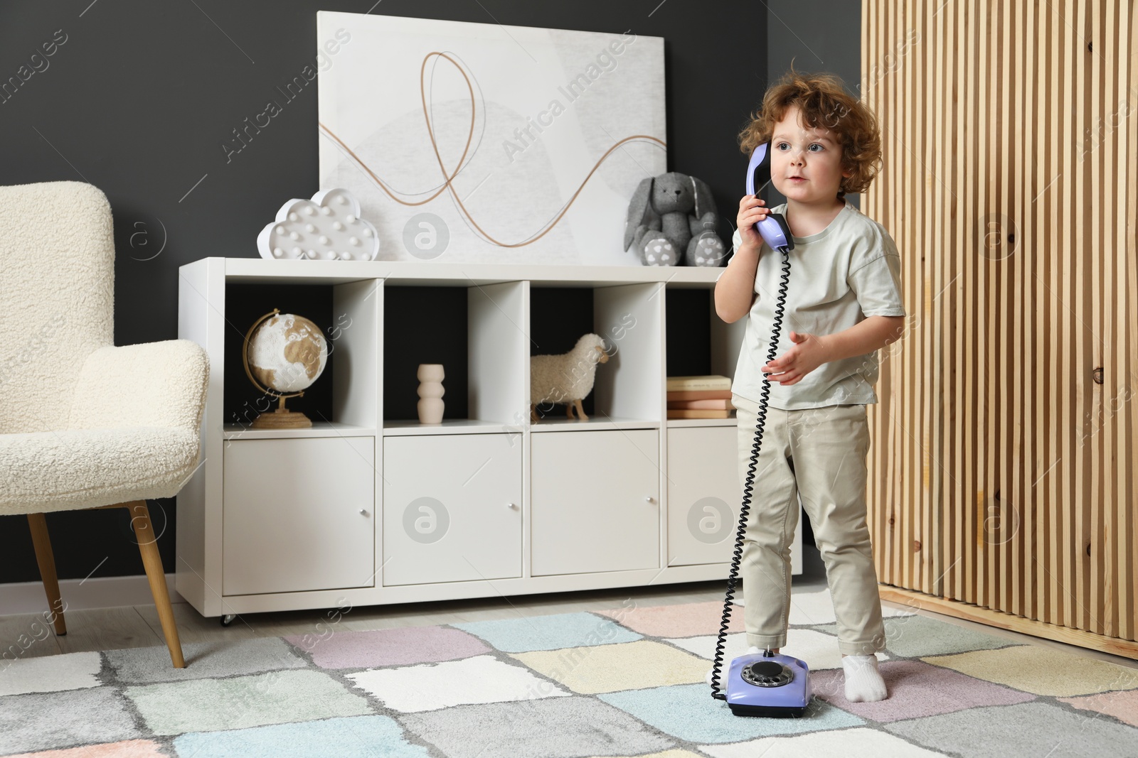 Photo of Cute little boy with telephone at home