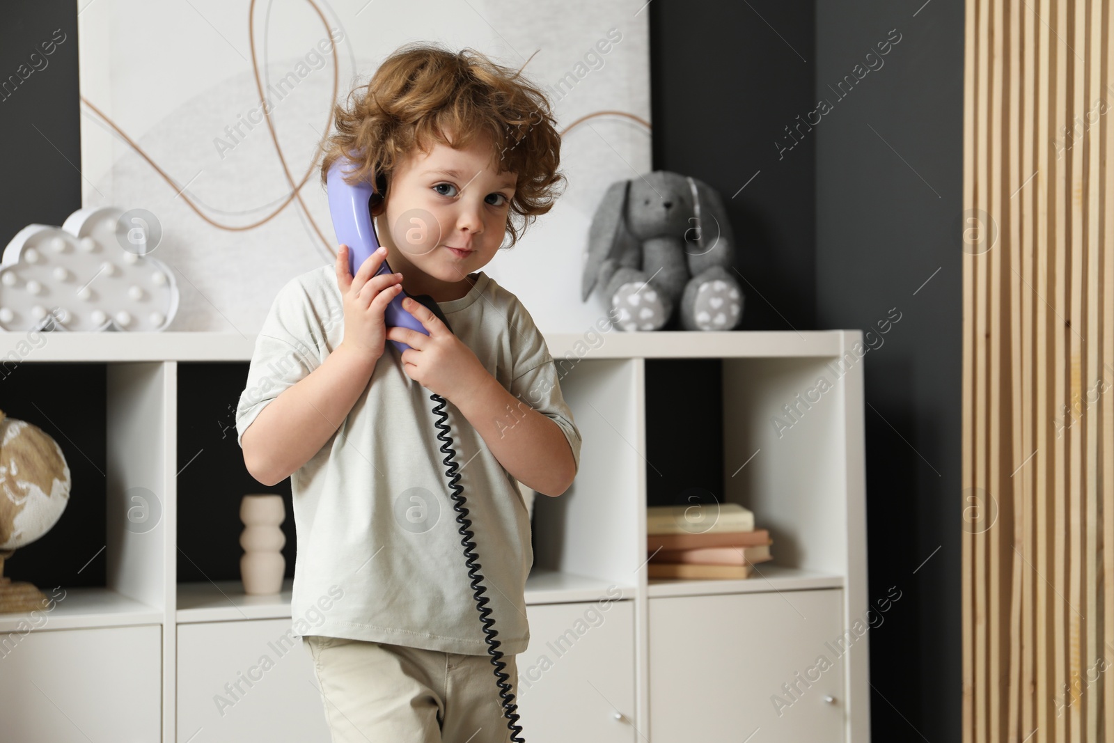 Photo of Cute little boy with telephone handset indoors, space for text