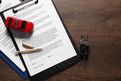 Photo of Car key, model and purchase agreement on wooden table, flat lay. Buying auto