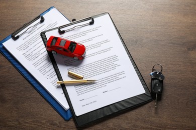 Photo of Car key, model and purchase agreement on wooden table. Buying auto