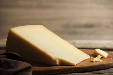 Photo of Piece of delicious cheese on wooden table, closeup