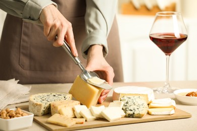 Photo of Woman slicing delicious cheese at light textured table indoors, closeup