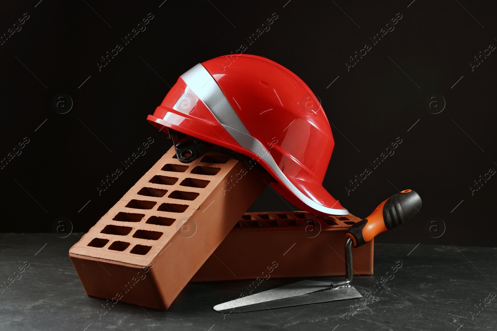 Photo of Bricks, hardhat and bucket trowel on grey table