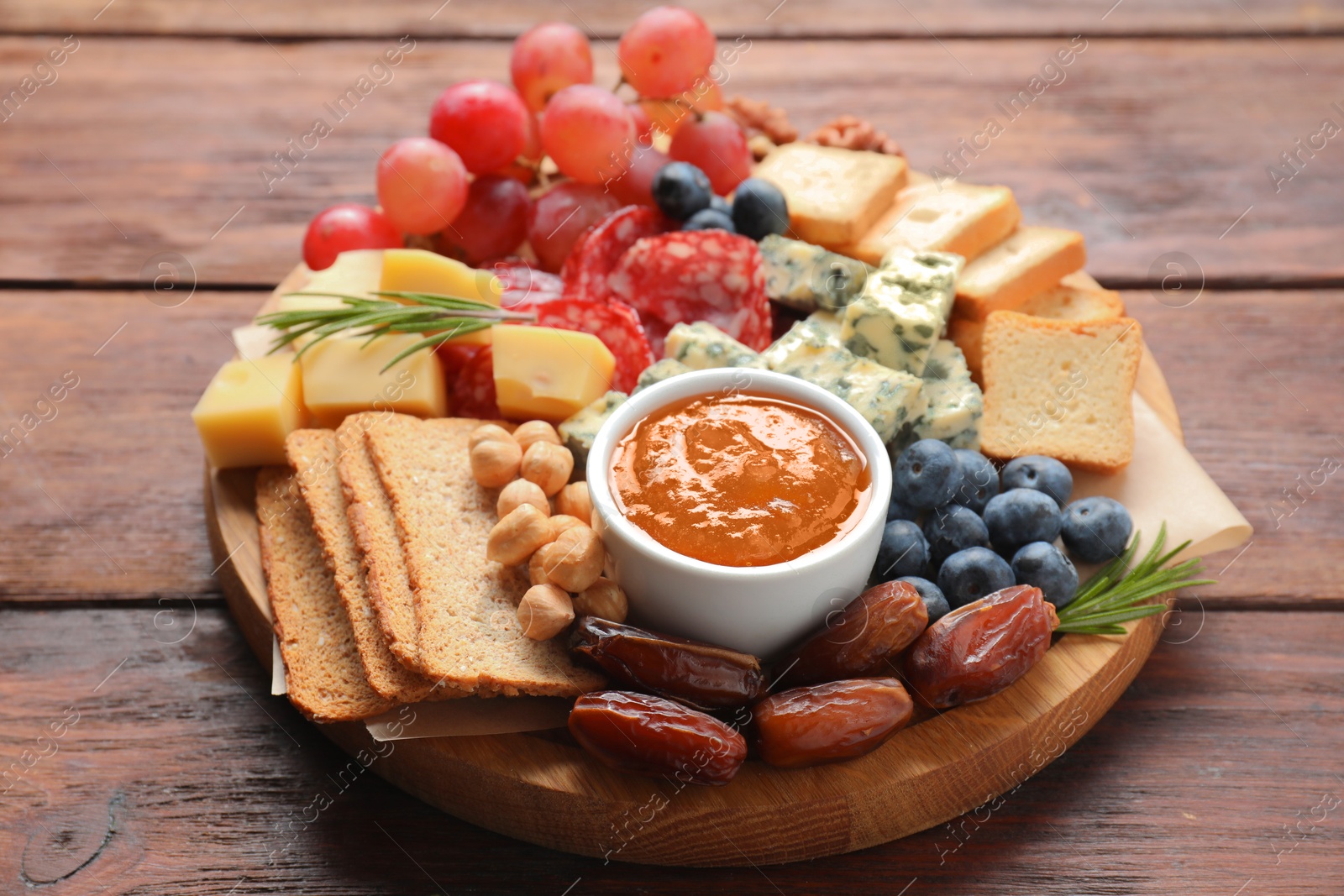 Photo of Different types of delicious cheese and other snacks on wooden table, closeup