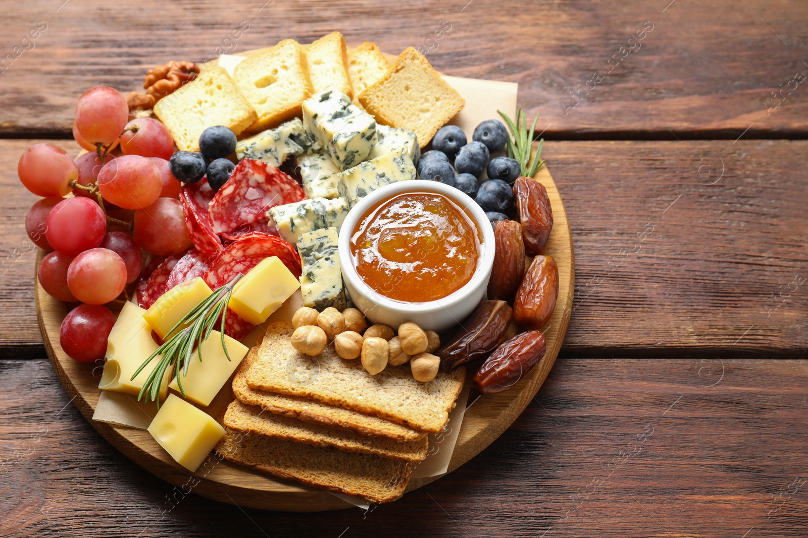 Photo of Different types of delicious cheese and other snacks on wooden table, above view. Space for text