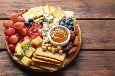 Photo of Different types of delicious cheese and other snacks on wooden table, above view. Space for text