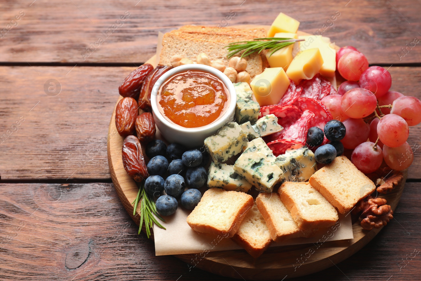 Photo of Different types of delicious cheese and other snacks on wooden table, closeup. Space for text