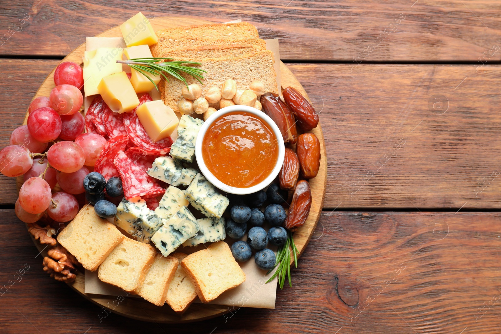 Photo of Different types of delicious cheese and other snacks on wooden table, top view. Space for text