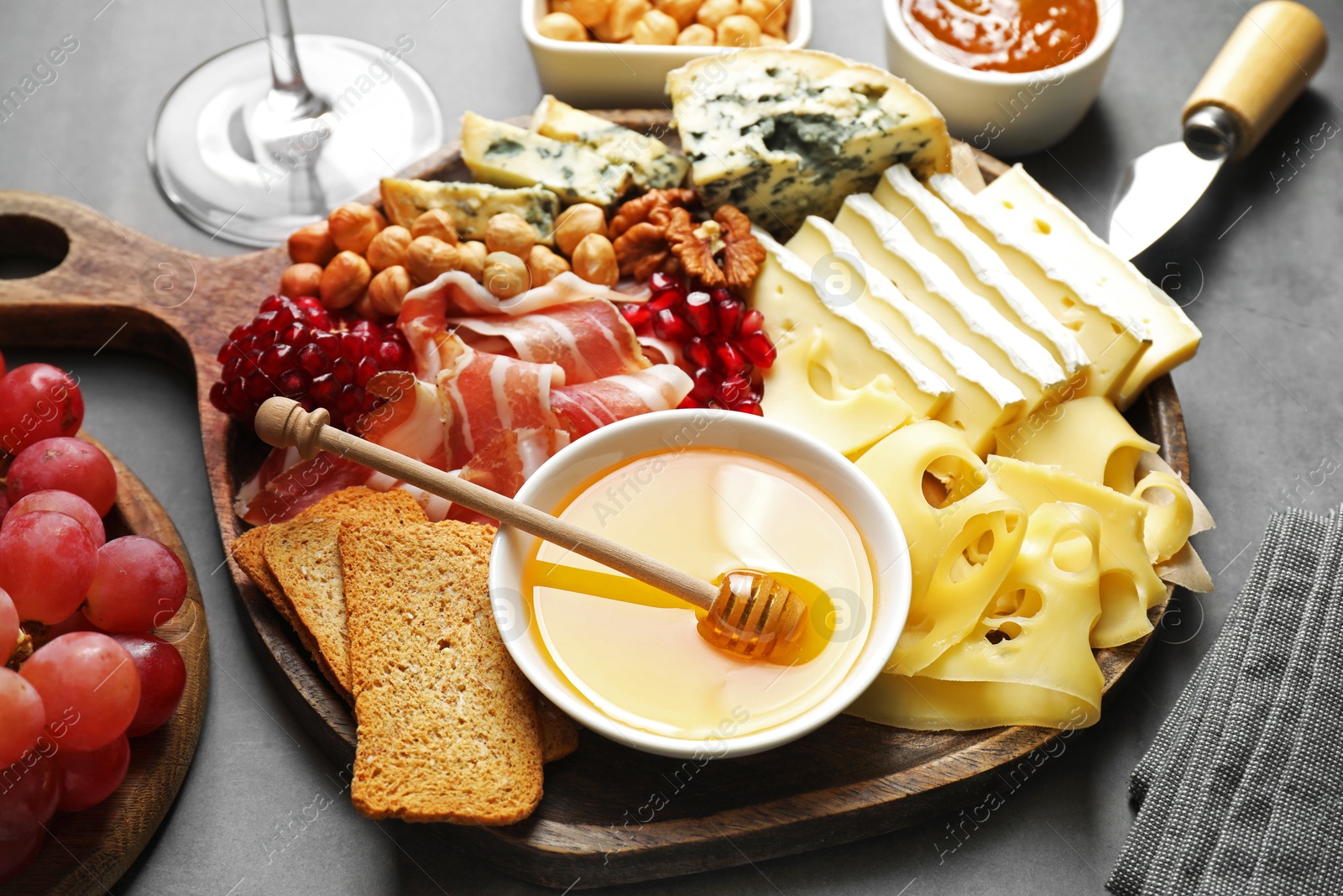 Photo of Different types of cut cheese and other snacks on gray table, closeup