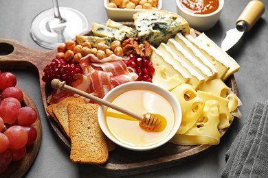 Photo of Different types of cut cheese and other snacks on gray table, closeup