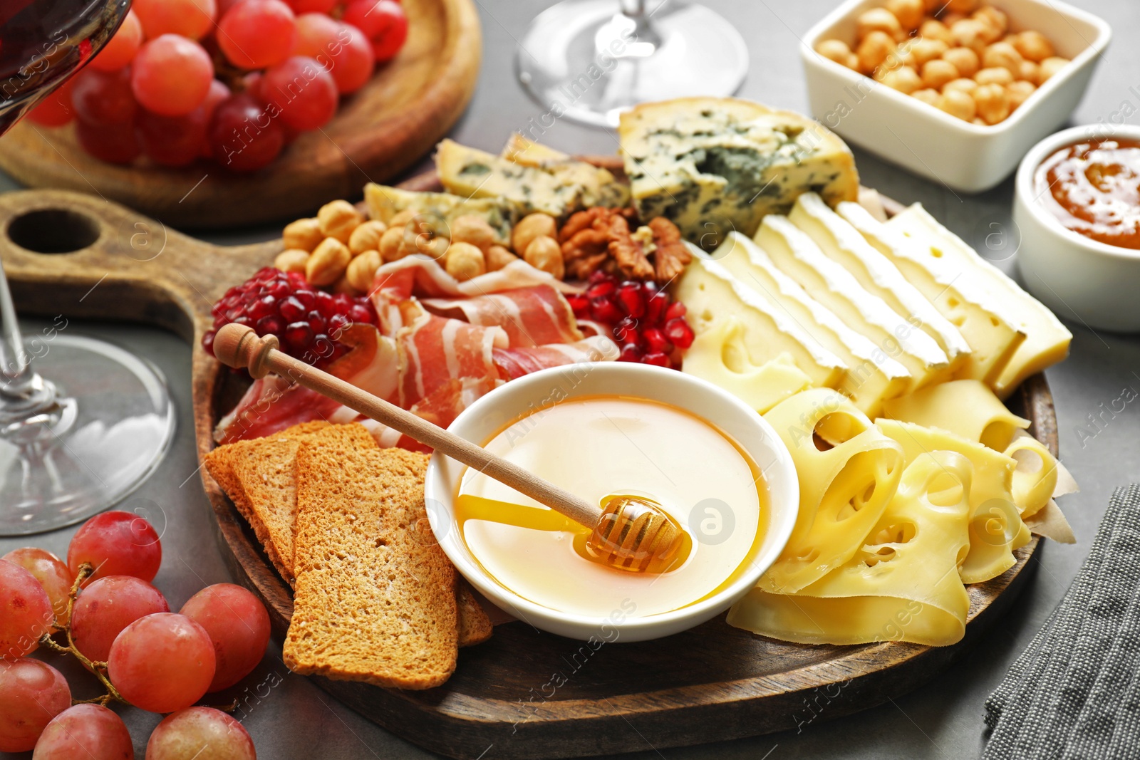 Photo of Different types of cut cheese and other snacks on gray table, closeup