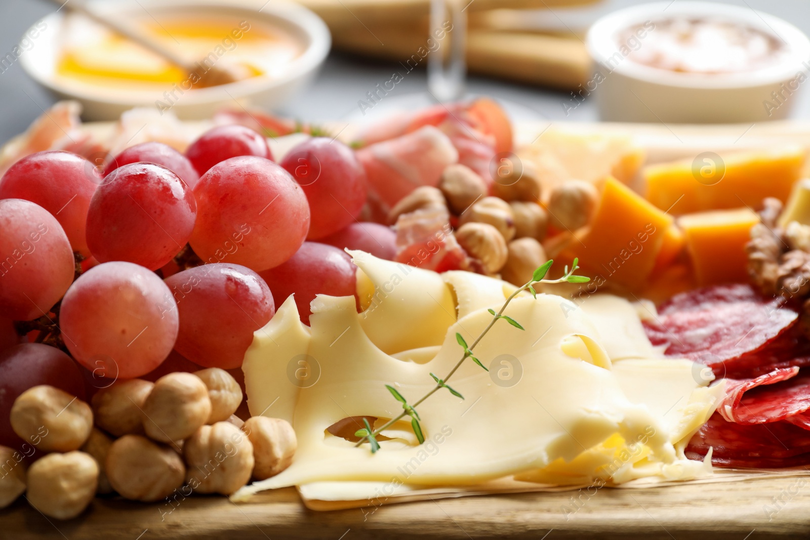 Photo of Different types of cut cheese and other snacks on table, closeup