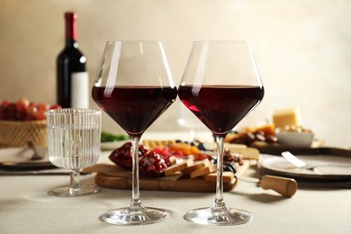 Photo of Red wine and different snacks served on light grey table