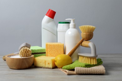 Photo of Eco-friendly cleaning products and supplies on wooden table against grey background