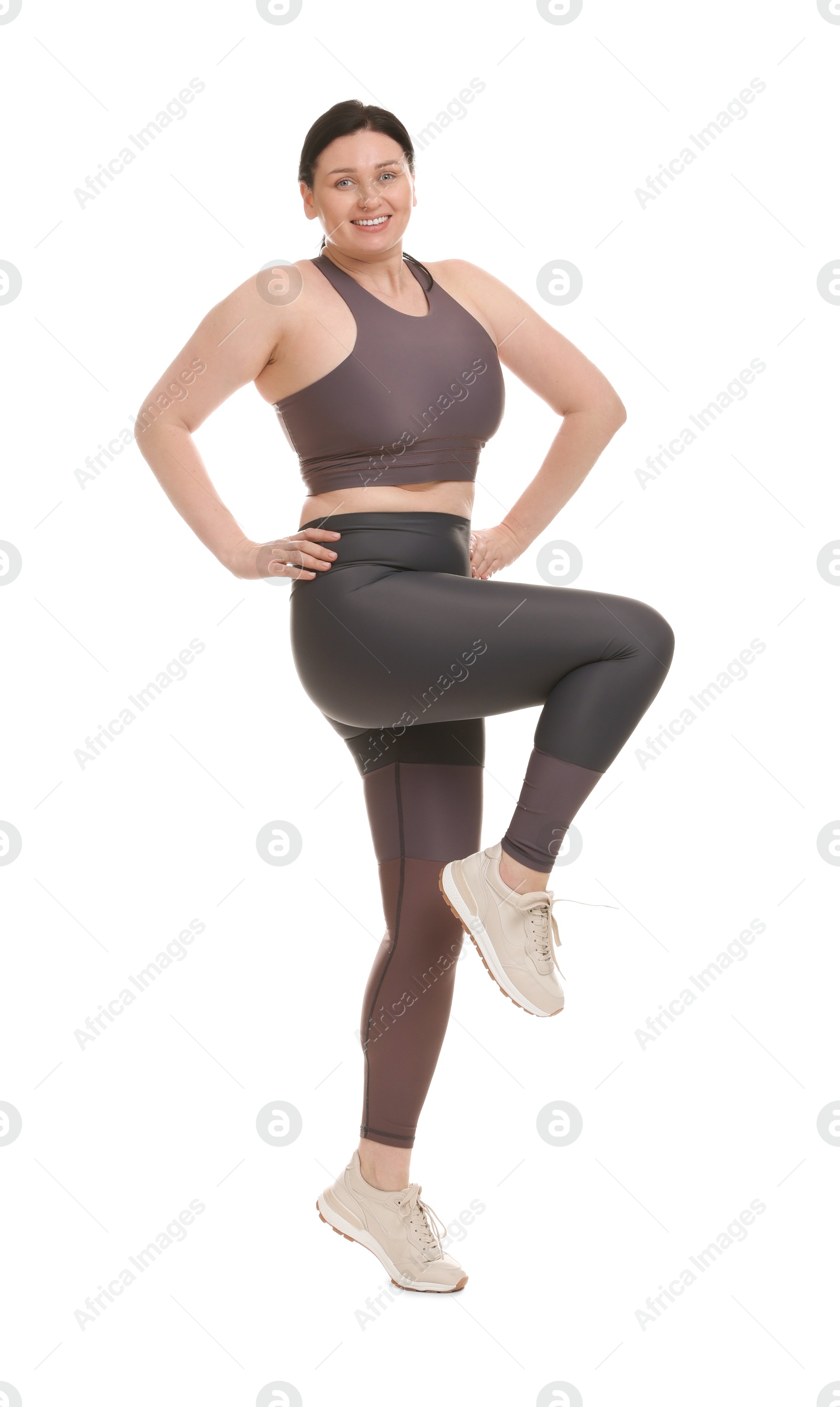 Photo of Plus size woman in gym clothes exercising on white background