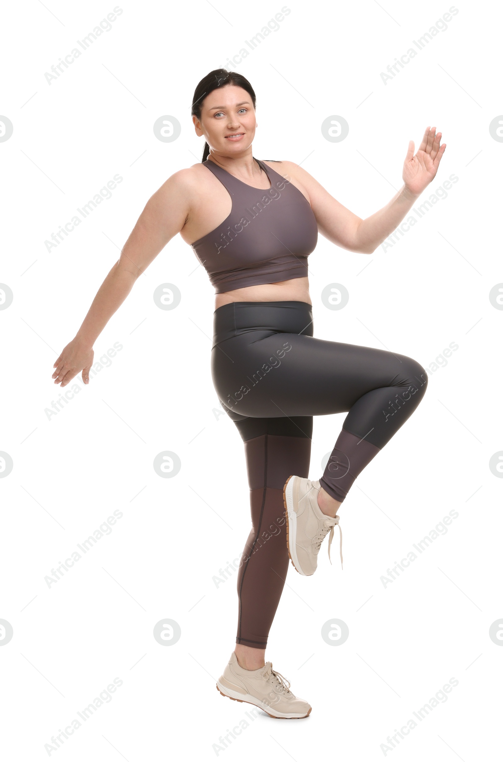 Photo of Plus size woman in gym clothes exercising on white background