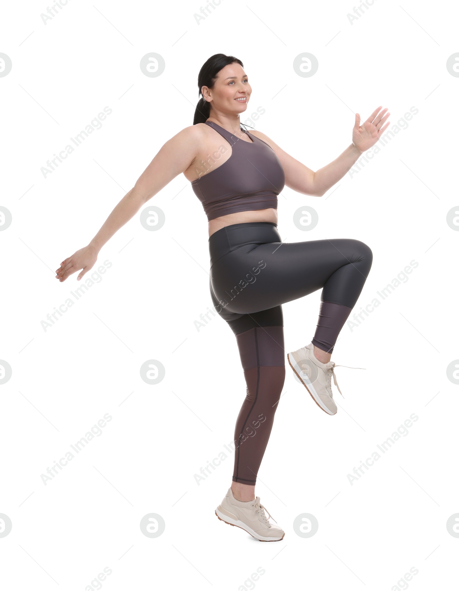 Photo of Plus size woman in gym clothes exercising on white background