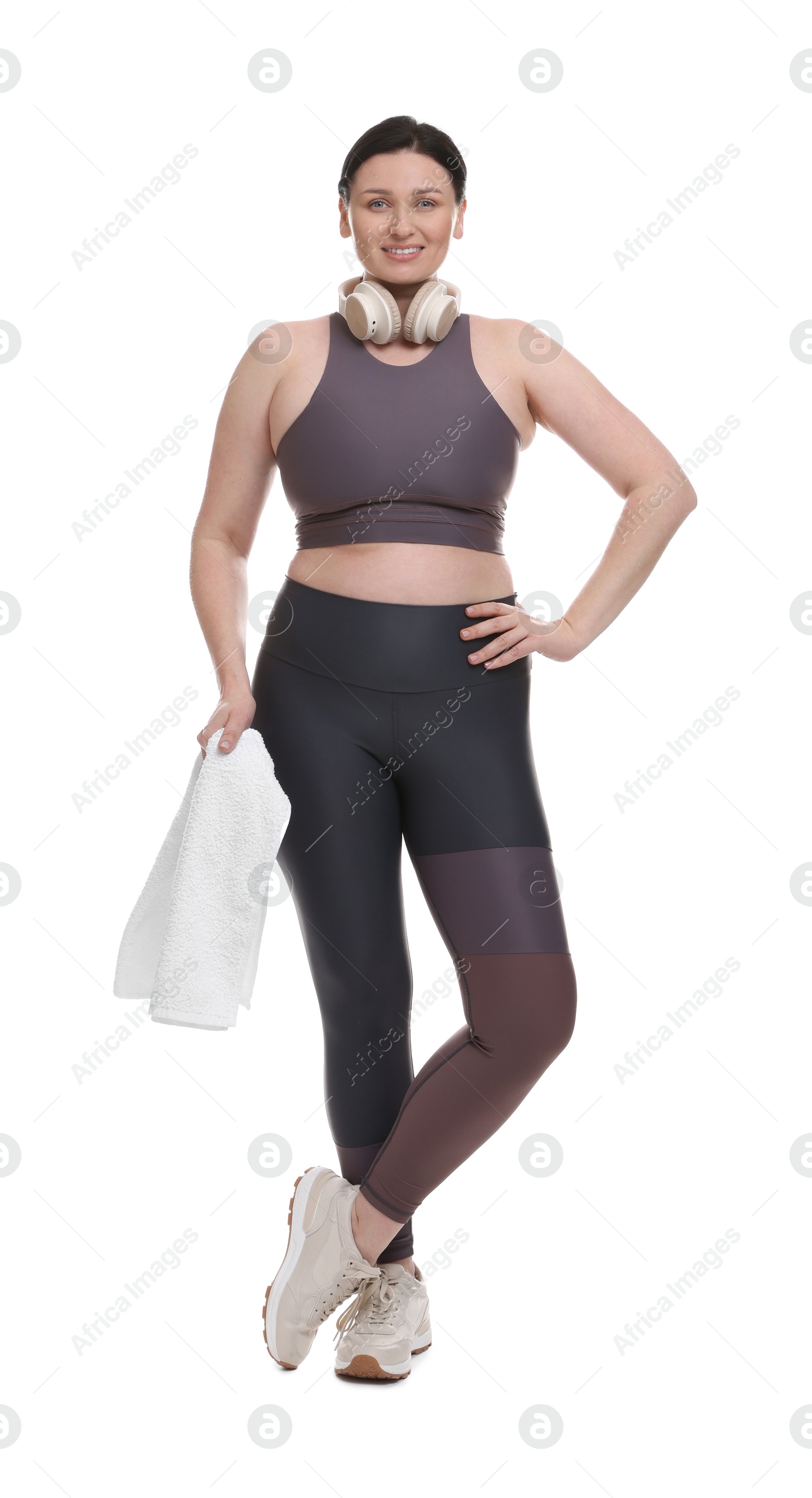 Photo of Plus size woman in gym clothes with headphones and towel on white background