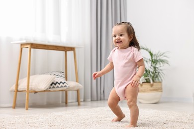 Photo of First steps. Cute little baby learning to walk at home