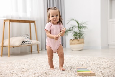 Photo of First steps. Cute little baby with drumsticks learning to walk at home