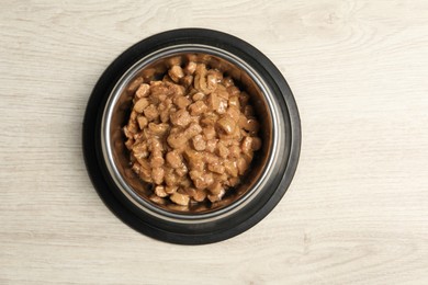 Photo of Wet pet food in feeding bowl on floor, top view