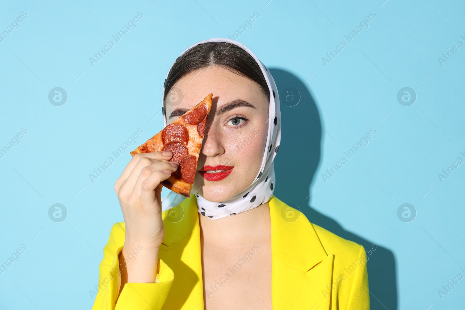 Photo of Stylish woman with piece of pizza on light blue background