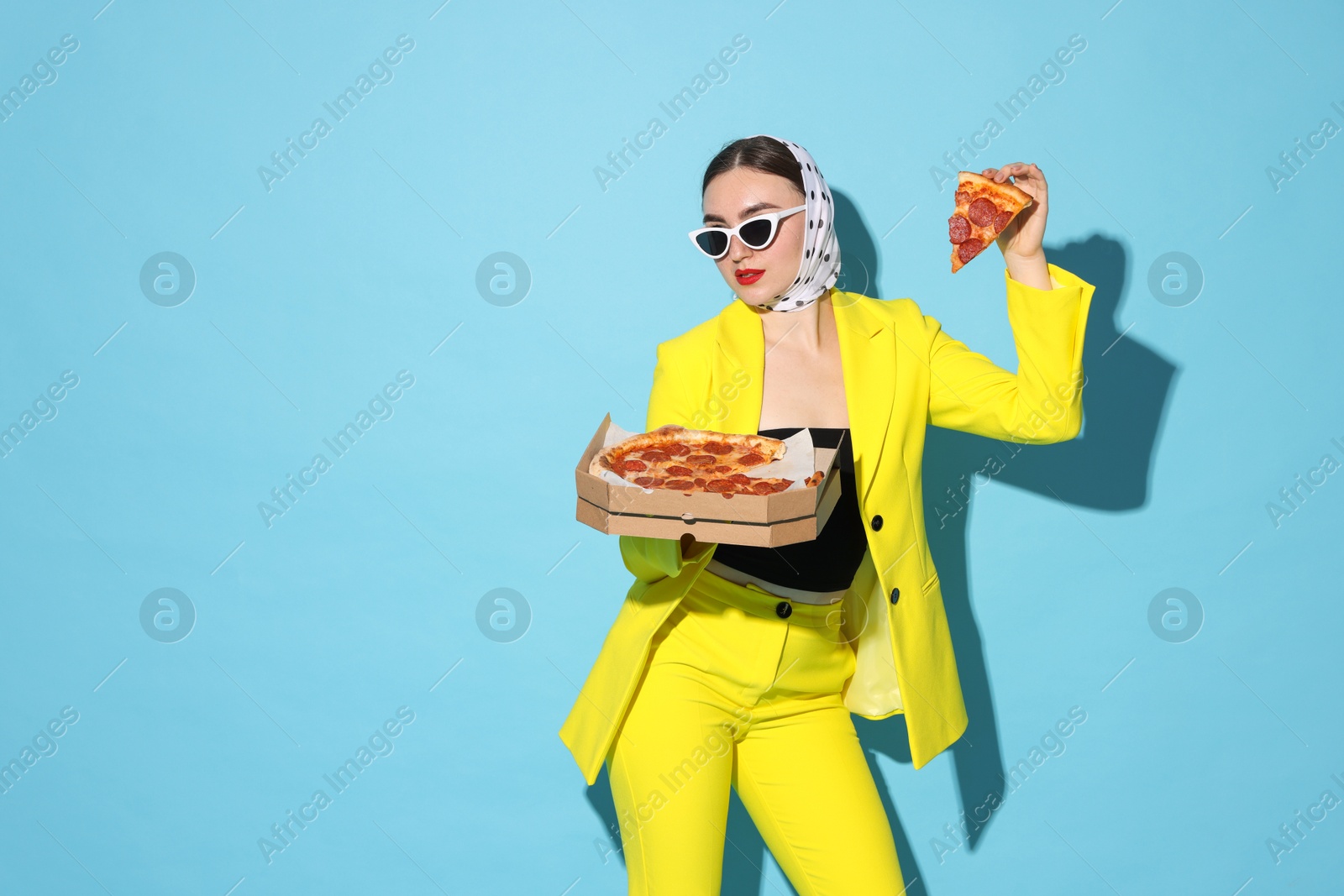 Photo of Stylish woman with delicious pizza on light blue background, space for text