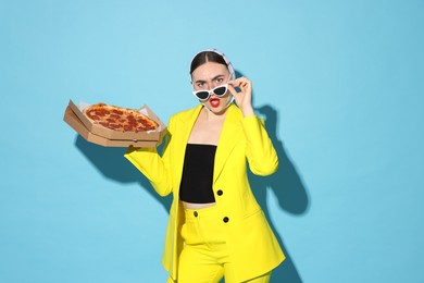 Photo of Stylish woman with delicious pizza on light blue background