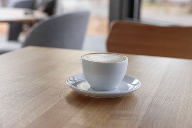 Photo of Cup of aromatic coffee on wooden table in cafe