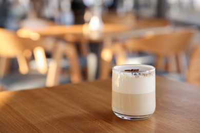 Photo of Glass of aromatic coffee on wooden table in cafe, closeup. Space for text