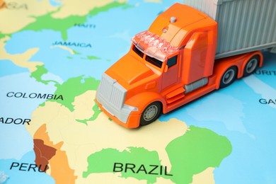 Photo of Toy truck on world map, closeup. Logistics concept