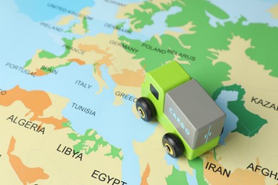 Photo of Toy truck on world map, closeup. Logistics concept