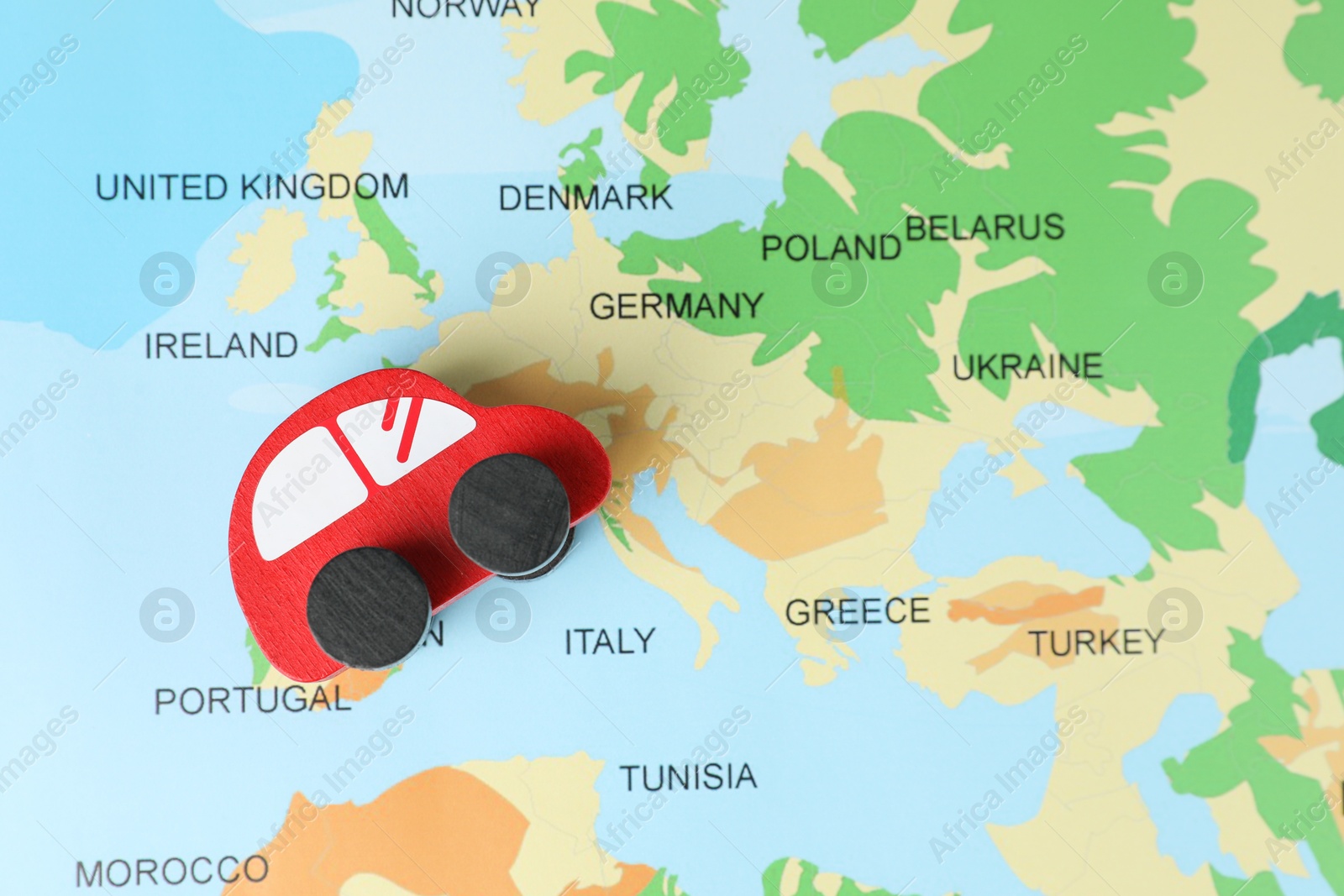 Photo of Red wooden toy car on world map, top view. Road trip