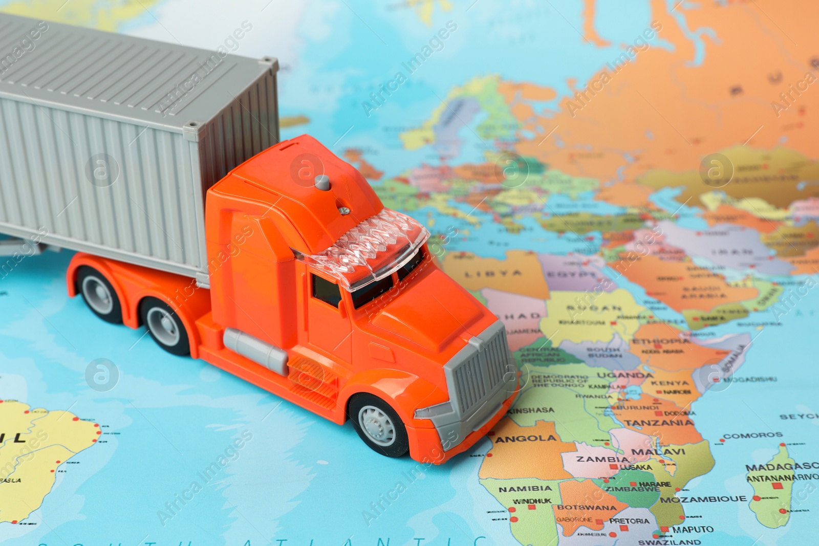 Photo of Toy truck on world map, closeup. Logistics concept