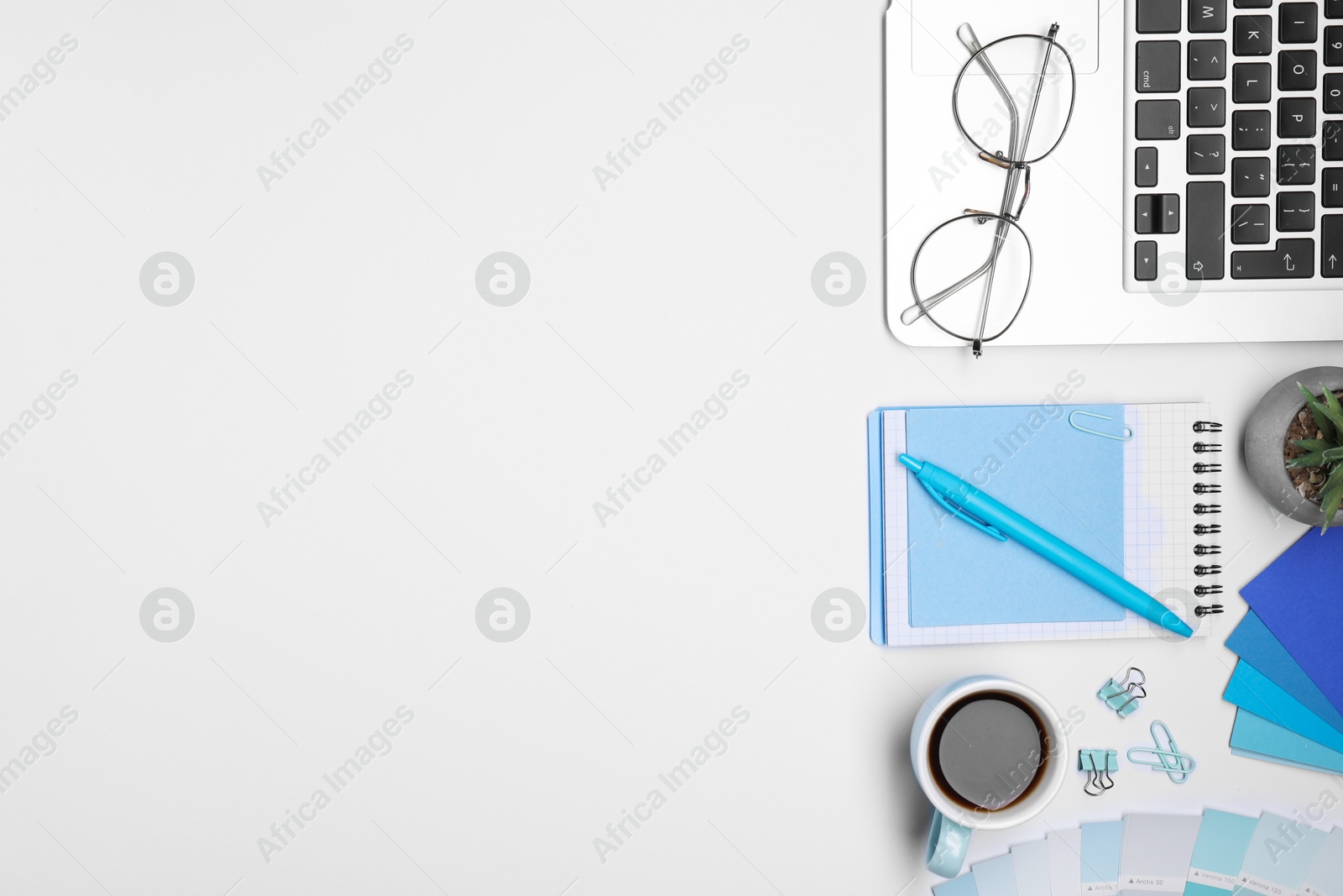 Photo of Designer's workplace with stationery, color palettes, cup of coffee and laptop on grey table, flat lay. Space for text