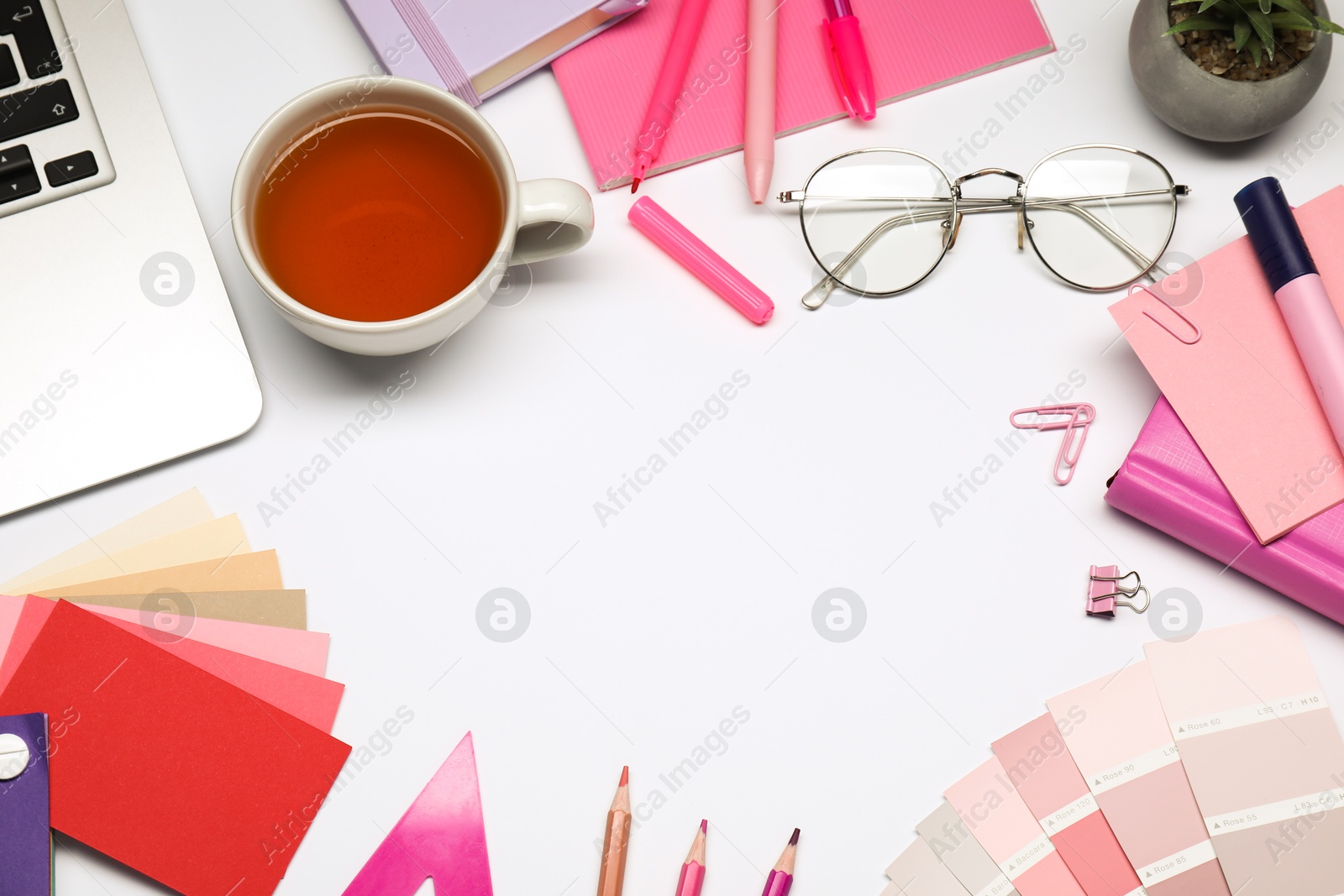 Photo of Designer's workplace. Frame of different stationery, color palettes and cup of tea on grey table, flat lay. Space for text