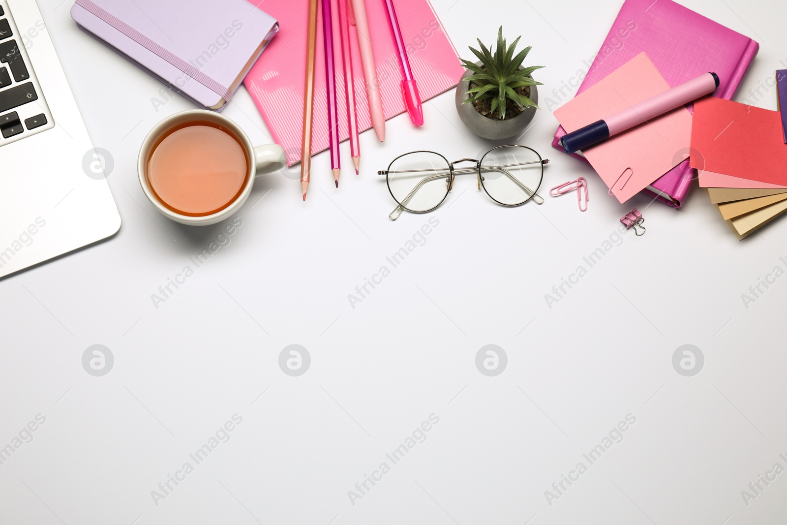 Photo of Designer's workplace with stationery, color palettes and cup of tea on grey table, flat lay. Space for text