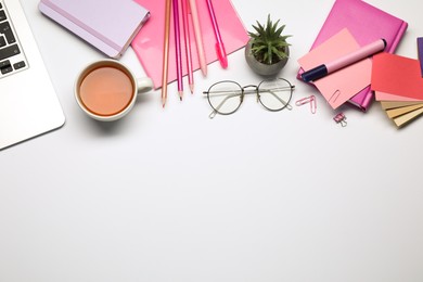 Photo of Designer's workplace with stationery, color palettes and cup of tea on grey table, flat lay. Space for text