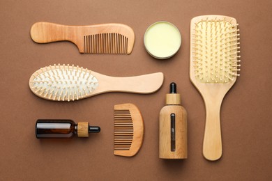 Photo of Wooden hair brushes, combs and cosmetic products on dark beige background, flat lay