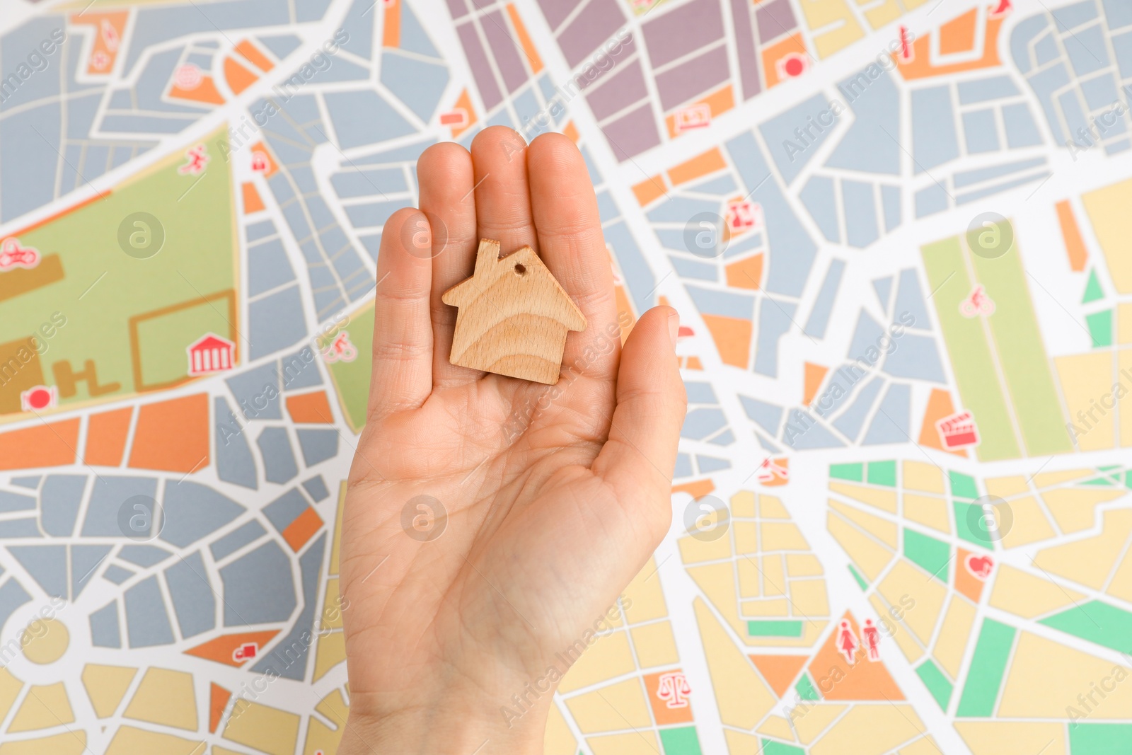 Photo of Woman holding wooden house model over city map, top view. Accommodation search