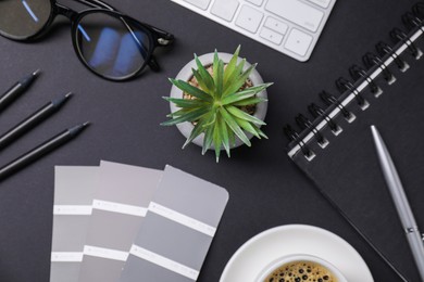 Photo of Designer's workplace with keyboard, stationery and cup of coffee on black background, flat lay