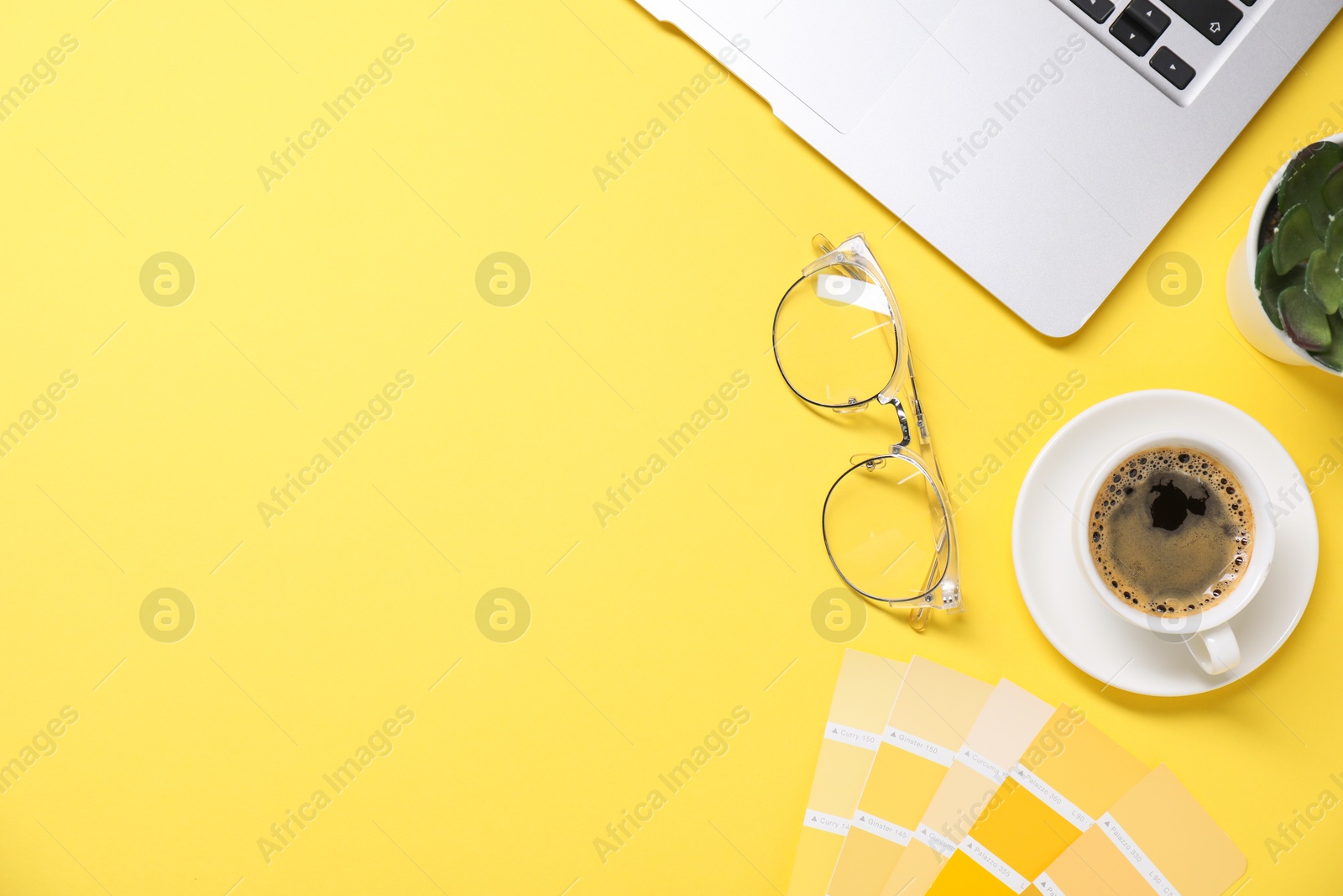 Photo of Designer's workplace with laptop, stationery and cup of coffee on yellow background, flat lay. Space for text