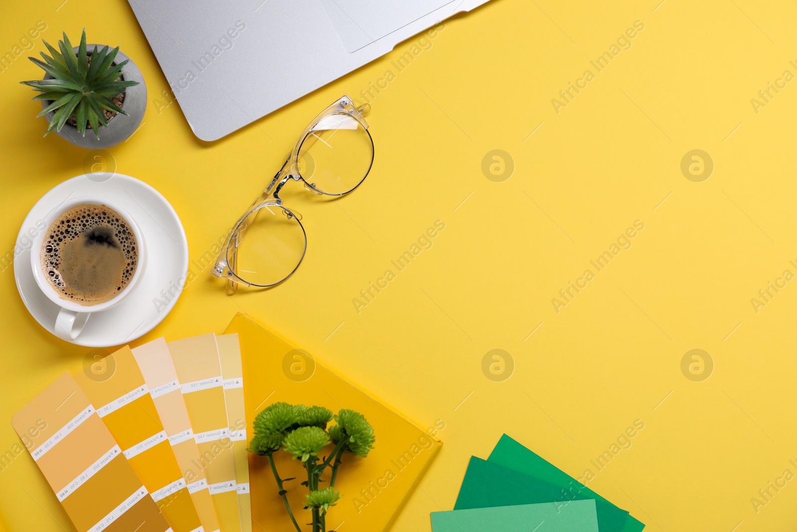 Photo of Designer's workplace with laptop, stationery and cup of coffee on yellow background, flat lay. Space for text