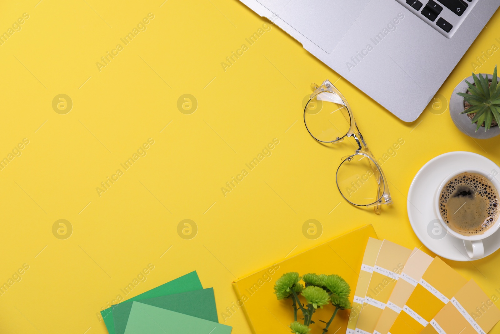 Photo of Designer's workplace with laptop, stationery and cup of coffee on yellow background, flat lay. Space for text