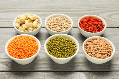 Photo of Superfood. Different healthy food products in bowls on grey wooden table, closeup