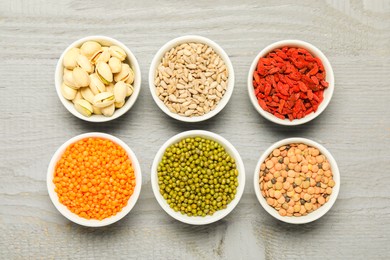 Photo of Superfood. Different healthy food products in bowls on grey wooden table, flat lay