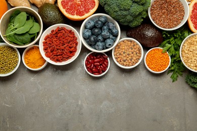 Photo of Superfood. Different healthy food products on grey table, flat lay. Space for text