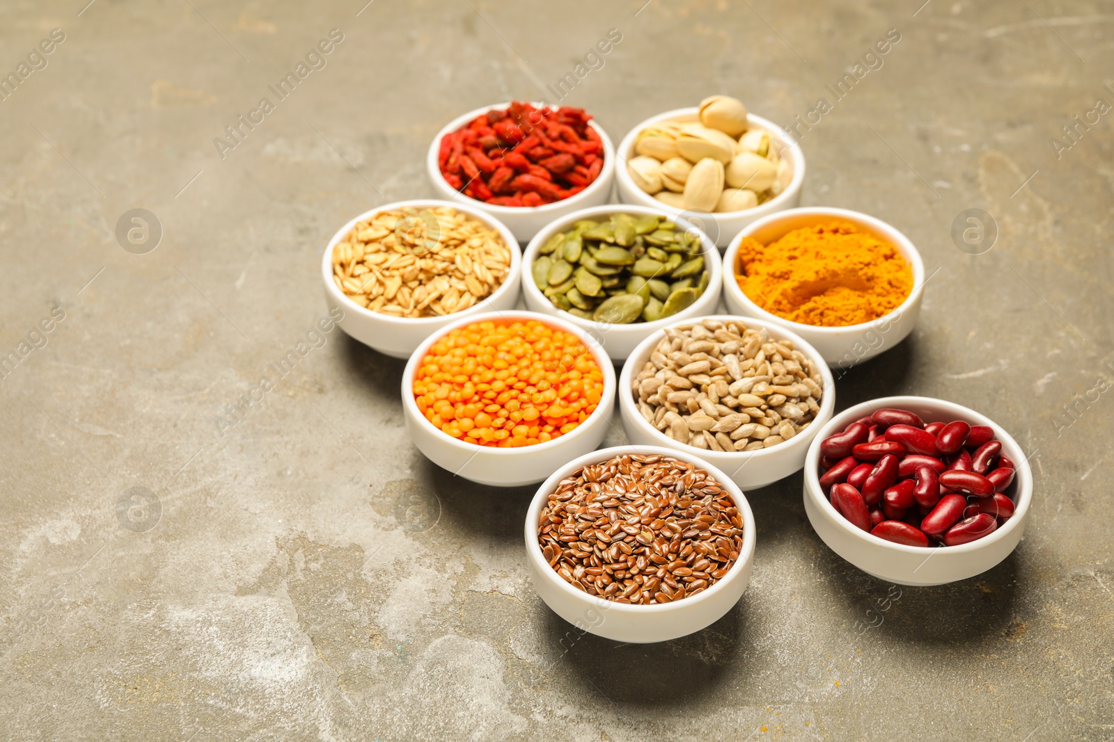 Photo of Different superfoods in bowls on grey table, space for text