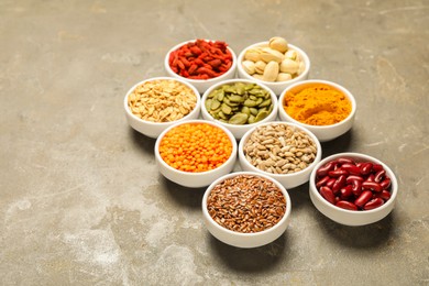 Photo of Different superfoods in bowls on grey table, space for text